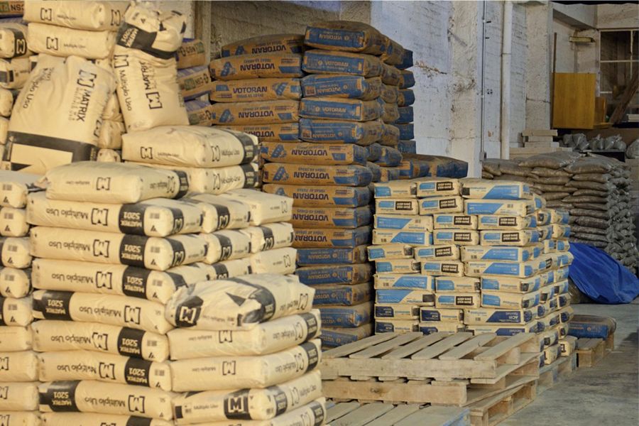 Sacos de cimento e argamassa empilhados em paletes no estoque da MB Materiais
